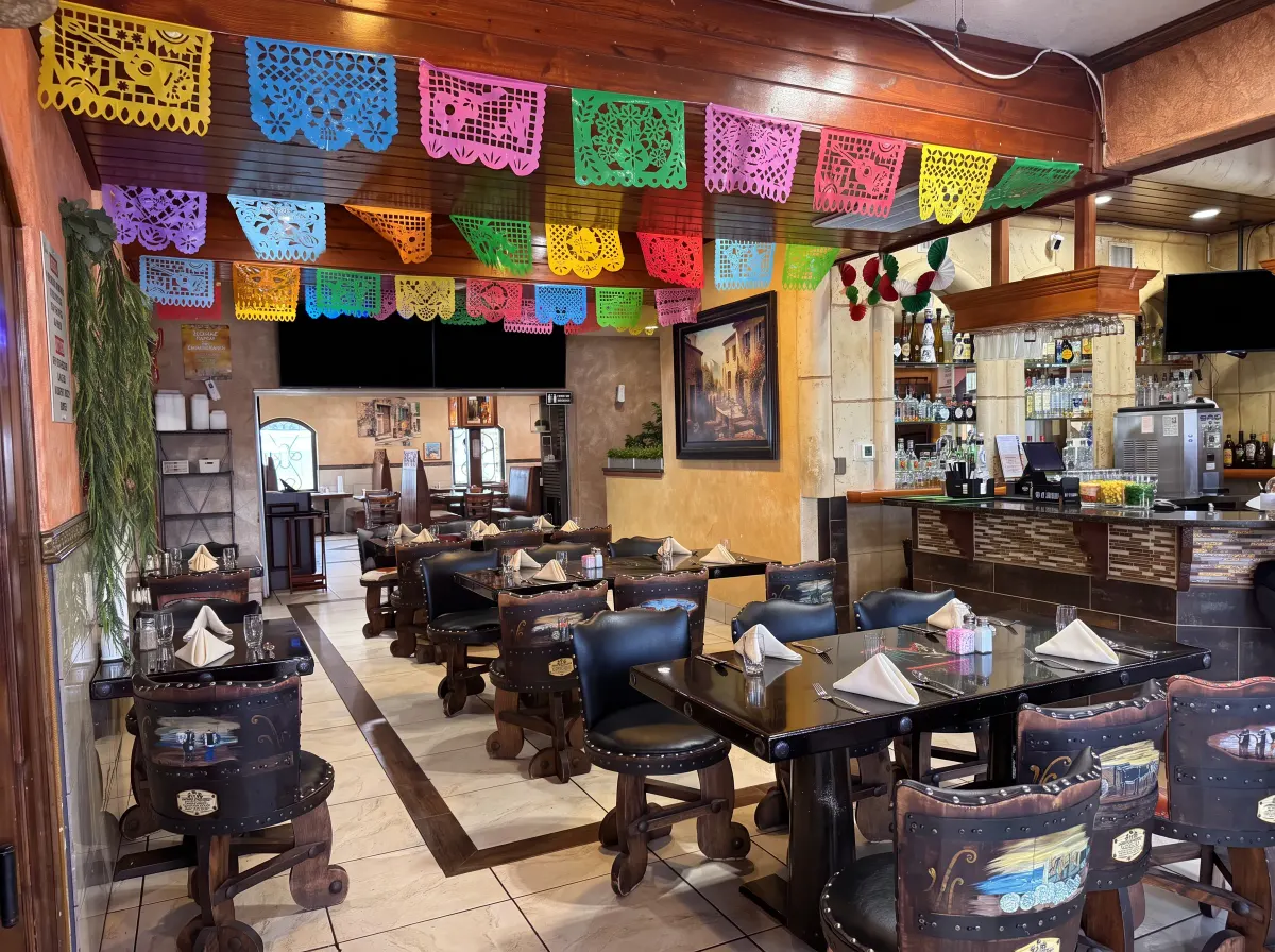 Comedor decorado con papel picado bajo vigas de madera tallada