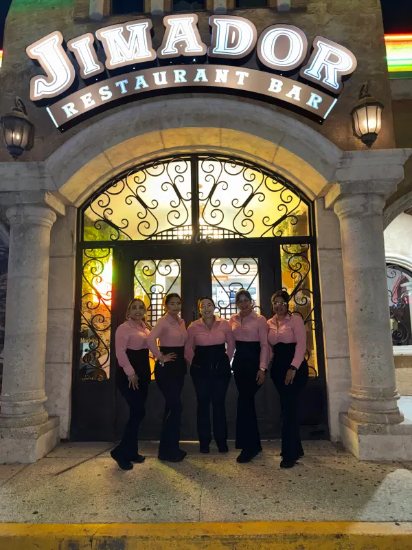 The lit Jimador Restaurant Bar sign above the arched entrance with its wrought-iron doors