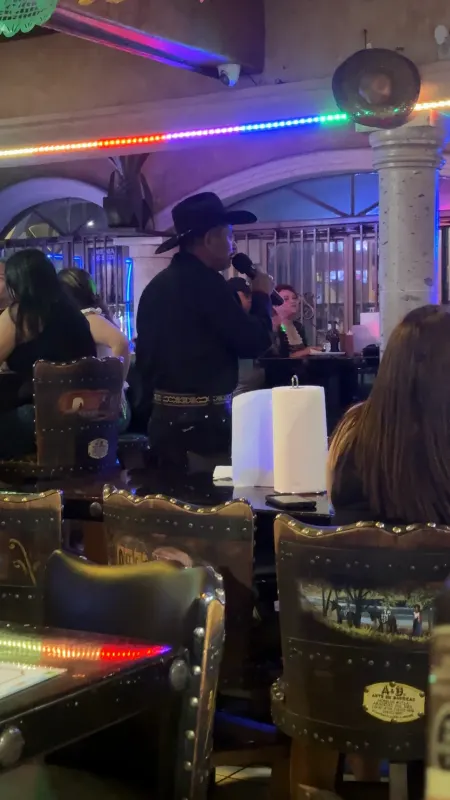 Singer with a microphone under strings of papel picado on karaoke night