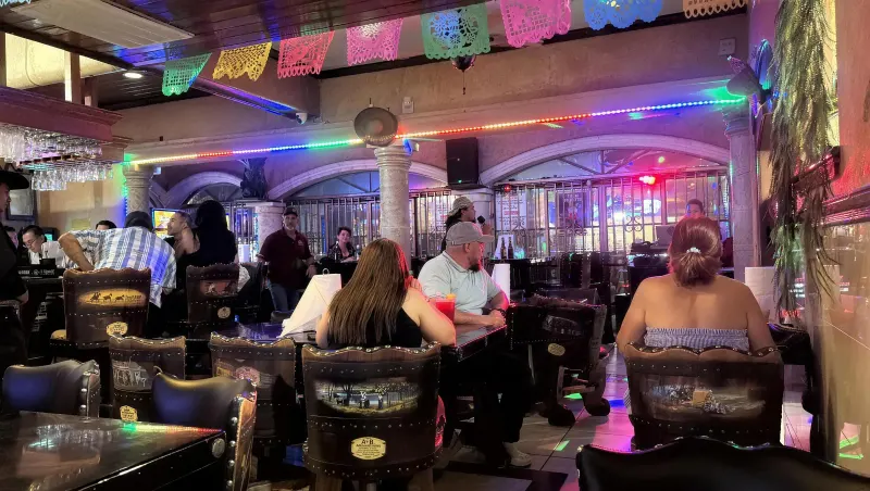 The dining room at night, full of guests seated beneath papel picado banners and a colored LED strip lit along the stone arches