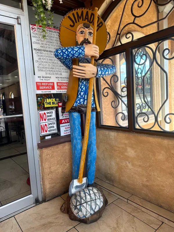 The carved figure of a jimador standing by the restaurant entrance